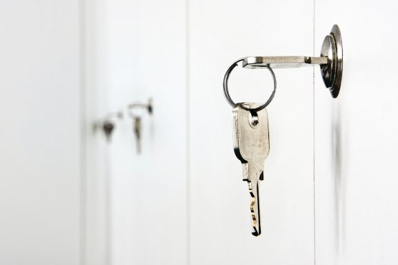 Clé en métal accrochée à une serrure sur une porte blanche.